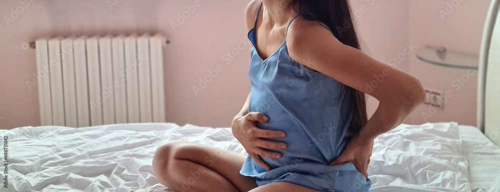 Pregnant woman suffers from lower back pain on bed - obrazy, fototapety, plakaty 