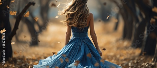 fantasy woman walking in autumn forest. an elegant blue dress fluttered in the wind. faceless photo