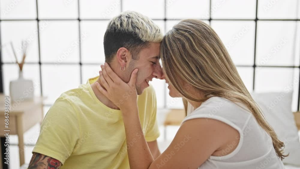 Beautiful couple sitting on bed touching nose at bedroom Beautiful couple sitting on bed touching nose at bedroom