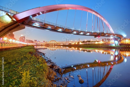 The famous Rainbow Bridge over Keelung River with reflections in the water at blue dusk, in Taipei, Taiwan, Asia ~A romantic landmark of Taipei, the capital city of Taiwan, under beautiful evening sky photo