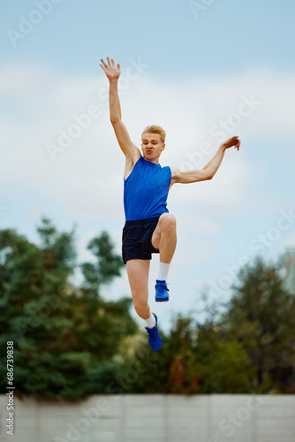 leap of determination frozen in this captivating long jump photo. motivated young man, professional sportsman doing perfect jump.
