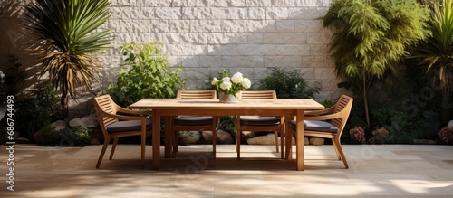 Stone table with ornamental plants and flower vases near minimalist wooden chairs on the terrace of the house