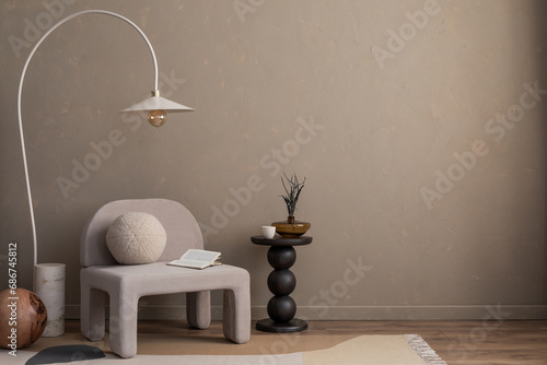 Minimalist composition of aesthetic living room interior with mock up poster frame, copy space, gray armchair, vase with dried flowers, round pillow and personal accessories. Home decor. Template. photo