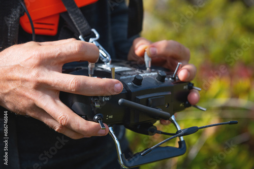 Close-up of a man's hands holding a transmitter and control equipment for an FPV drone quadcopter. Drone control concept
