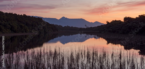 Sunset over a marsh with Mount Aspiring National Park in the background; Haast, Ship Creek, South Island, New Zealand photo