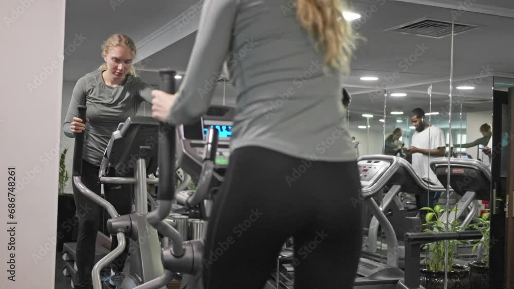 A woman with a sporty figure, in leggings, trains on an orbitrack in the gym A woman with a sporty figure, in leggings, trains on an orbitrack in the gym