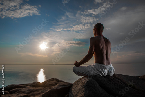 Man meditating in Lotus position by the Atlantic Ocean; Digby, Nova Scotia, Canada photo