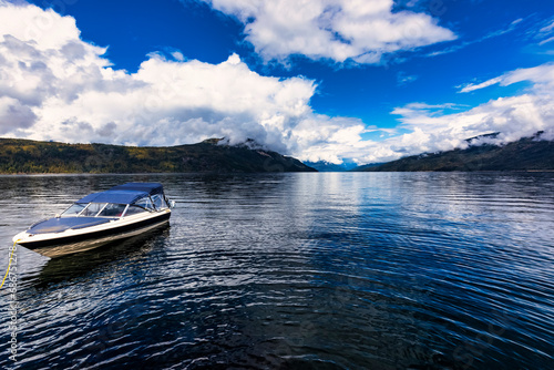 A small pleasure boat tied up on the shoreline of beautiful Shuswap Lake during the autumn season; Shuswap Lake, British Columbia, Canada