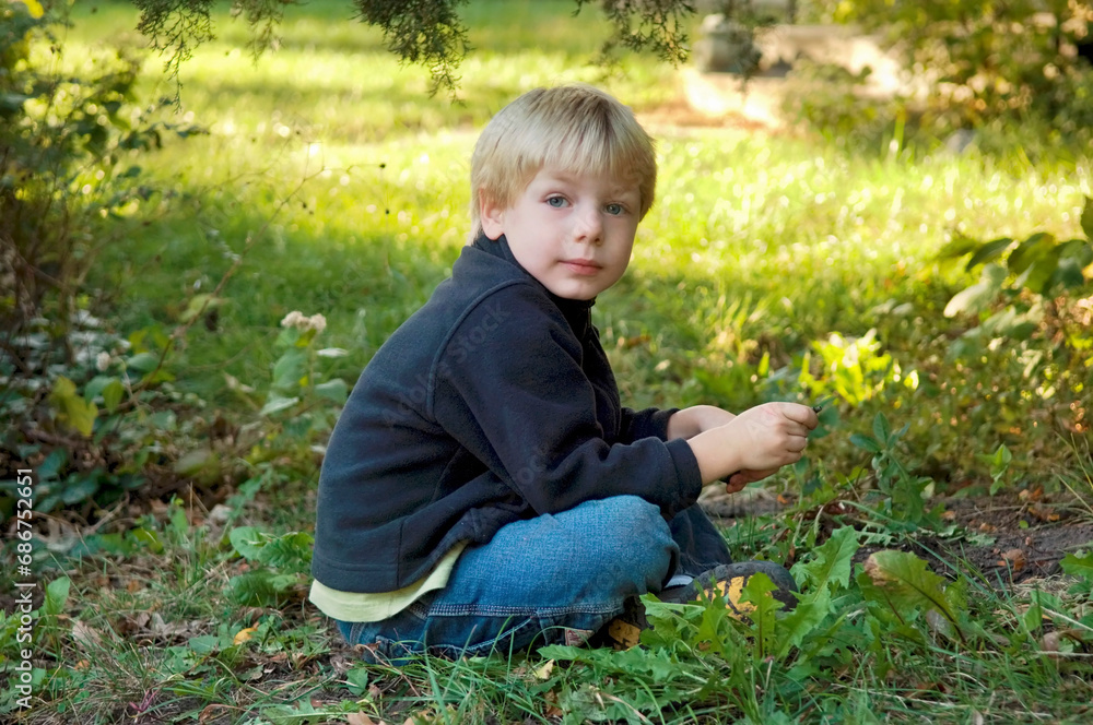 Young boy sits outdoors in a garden; Lincoln, Nebraska, United States of America Young boy sits outdoors in a garden; Lincoln, Nebraska, United States of America