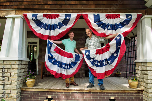 Two men hang up patriotic banners on the porch of a house; Lincoln, Nebraska, United States of America photo