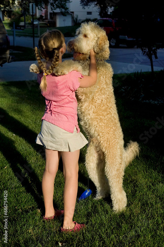 Young girl plays with her pet fanci doodle in her yard; Elkhorn, Nebraska, Unied States of America photo