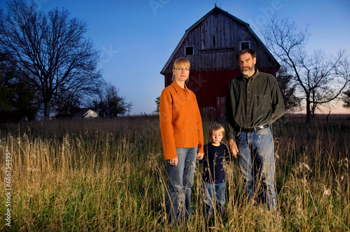 Family stands for a night portrait with a historic barn; Princeton, Nebraska, United States of America photo