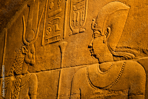 Close-up of bas-relief of hieroglyphs and mythology on the walls inside the Temple of Isis at Philae Island on the Nile River with golden light; Aswan, Egypt photo