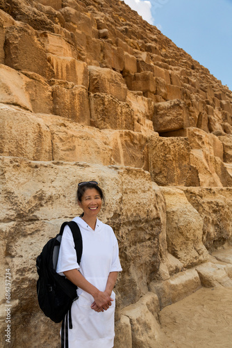 Close-up of an Asian female tourist standing in front of the Great Pyramid of Giza; Giza, Cairo, Egypt photo