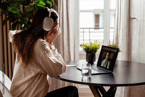 Young depressed woman having online session with psychologist at home. Sad girl crying during online therapy with her therapist