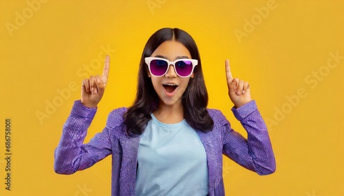 Amazed and surprised girl in sunglasses pointing fingers up.