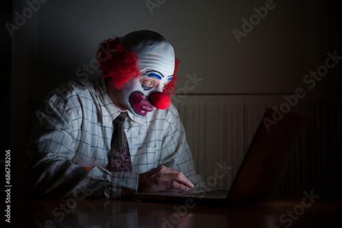Clown wearing a shirt and tie uses a laptop computer to surf the web, having a wide-eyed look of surprise on his face; Lincoln, Nebraska, United States of America