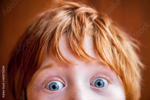 Close up of a young redhead with wide-eyed blue eyes; Studio photo