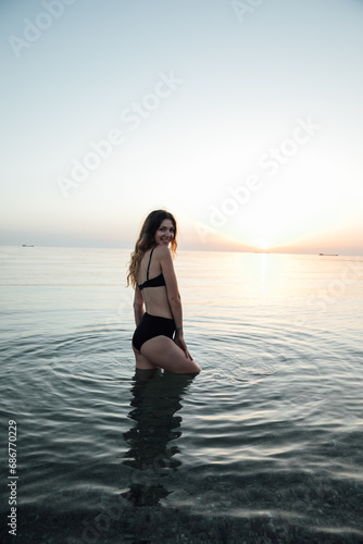 Beautiful slender woman in black swimsuit sunbathing on the beach
