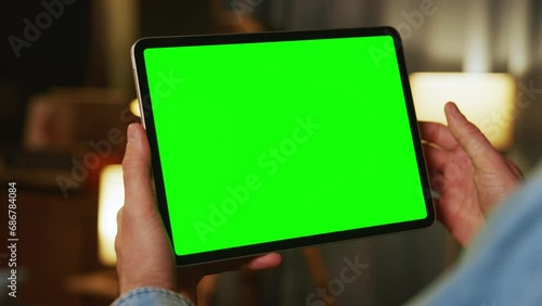 Hands man holding tapping on tablet computer with horizontal green screen. Mock up. In the evening
