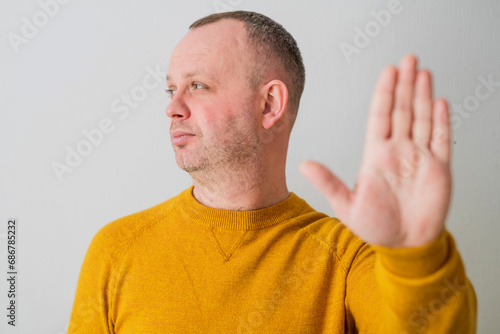 Portrait of young man's hand in yellow sweater saying stop or not accepting a new project. photo