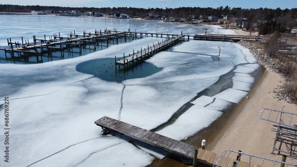 Aerial view of a tranquil winter scene featuring a lake partially covered in ice in Beaver Island Aerial view of a tranquil winter scene featuring a lake partially covered in ice in Beaver Island
