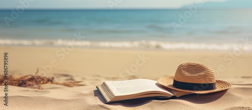 Sandy beach with book hat and towel near sea Copy space image Place for adding text or design