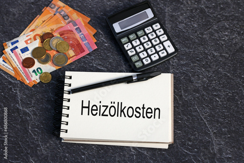 Das Wort Heizölkosten auf einen Notizblock geschrieben mit Euro Geldscheinen und Taschenrechner. photo