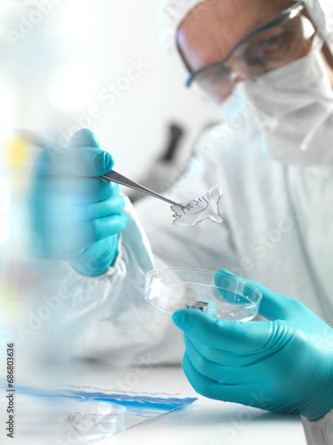 Forensic scientist examining fragments of paper in a laboratory