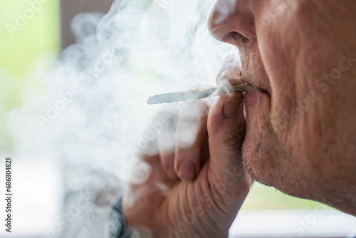 Senior man at home smoking marihuana joint