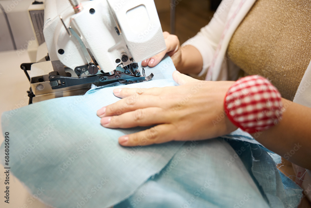 Lady works on a sewing machine with blue fabric