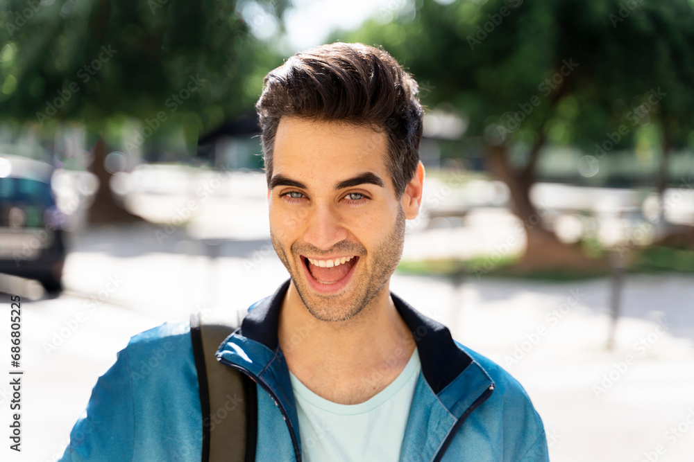 Happy man with bag standing in city during sunny day