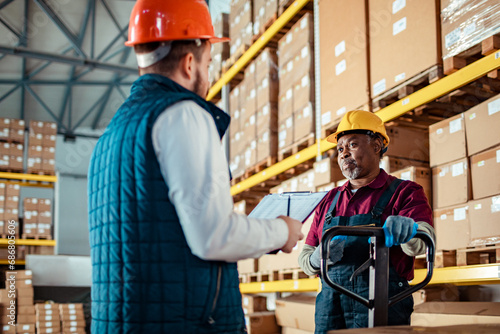 Two Workers Discussing Inventory in a Warehouse photo