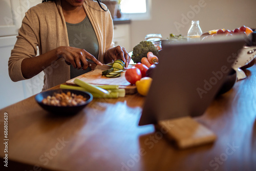Woman Preparing Fresh Vegetables with a Digital Recipe photo