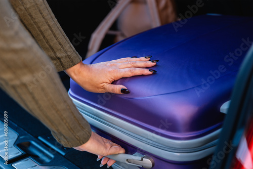 Hands of young woman loading her luggage in the trunk of the car. Concept of travel preparation © Beti Argi