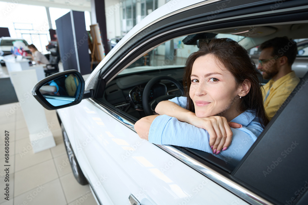 Pretty female posing at camera in car interior