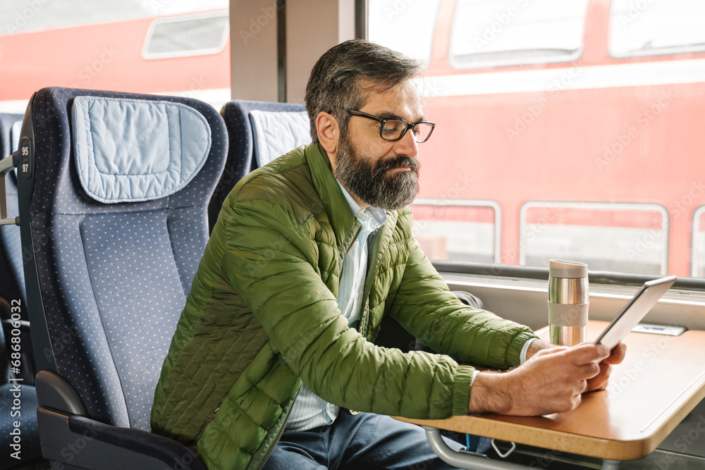 Man sitting in train using tablet