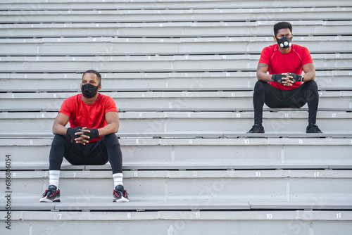 Two sportsmen wearing masks sitting on stairs photo