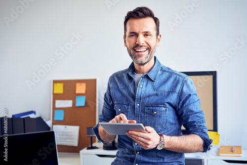 Portrait of smiling man using tablet in office