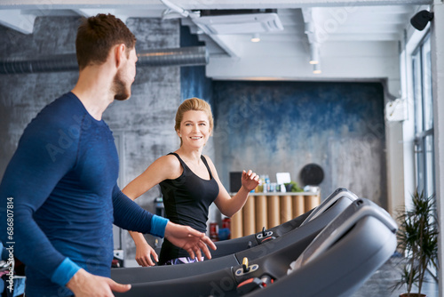 Man and woman talking during treadmill exercise at gym