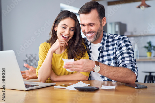 Couple sitting at dining table, using laptop, checking bills © tunedin