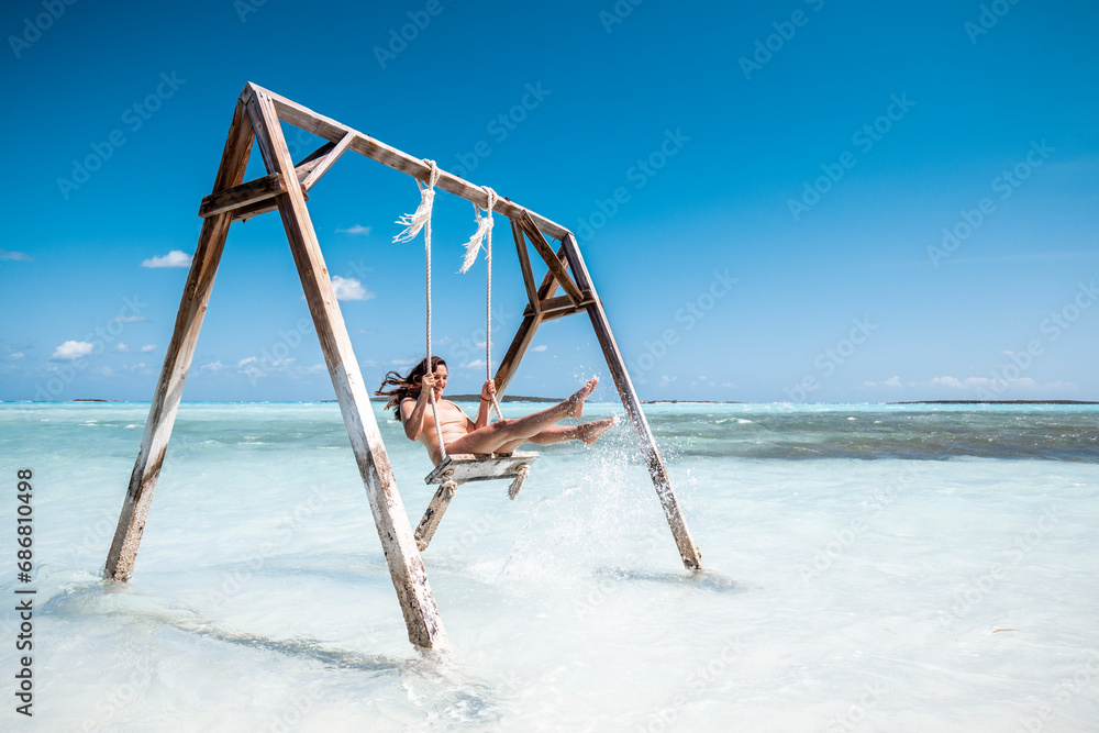 Woman swinging on swing in the sea, Bahamas, Caribbean Woman swinging on swing in the sea, Bahamas, Caribbean