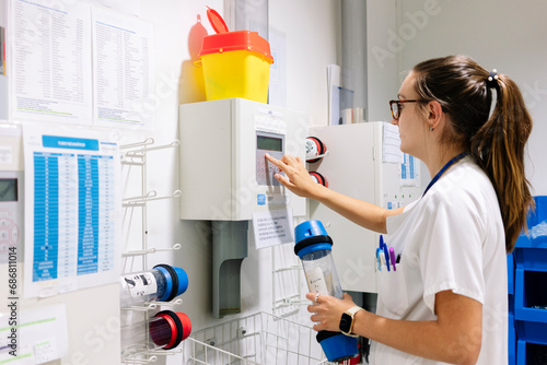 Female doctor using pneumatic tube system while standing in hospital photo