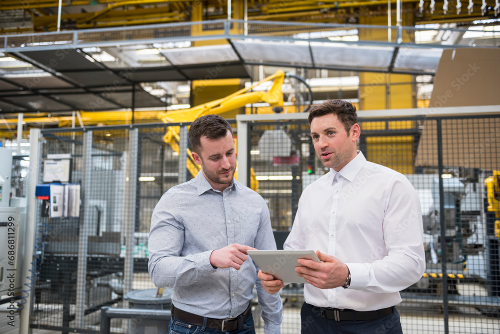 Two men with tablet talking in factory shop floor