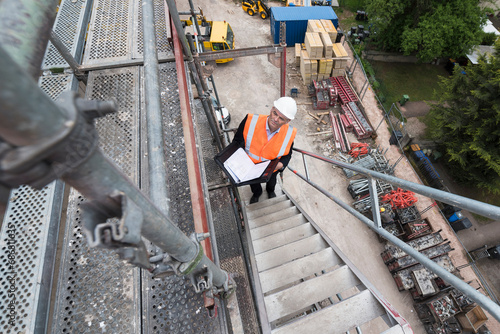 Man wearing safety vest on scaffolding on construction site photo