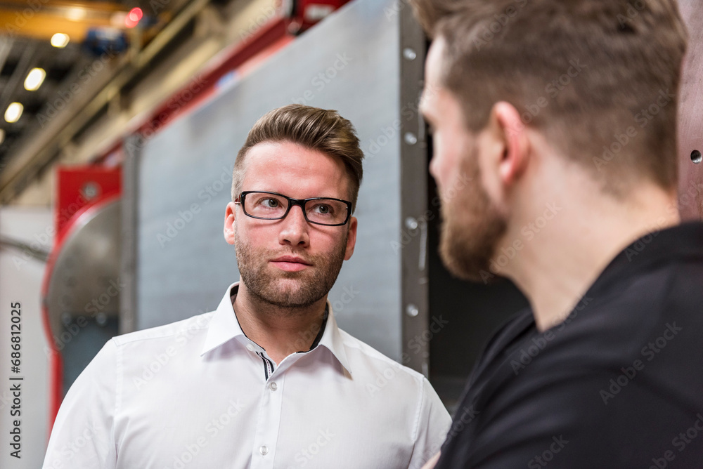 Portrait of businessman looking at employee in factory Portrait of businessman looking at employee in factory