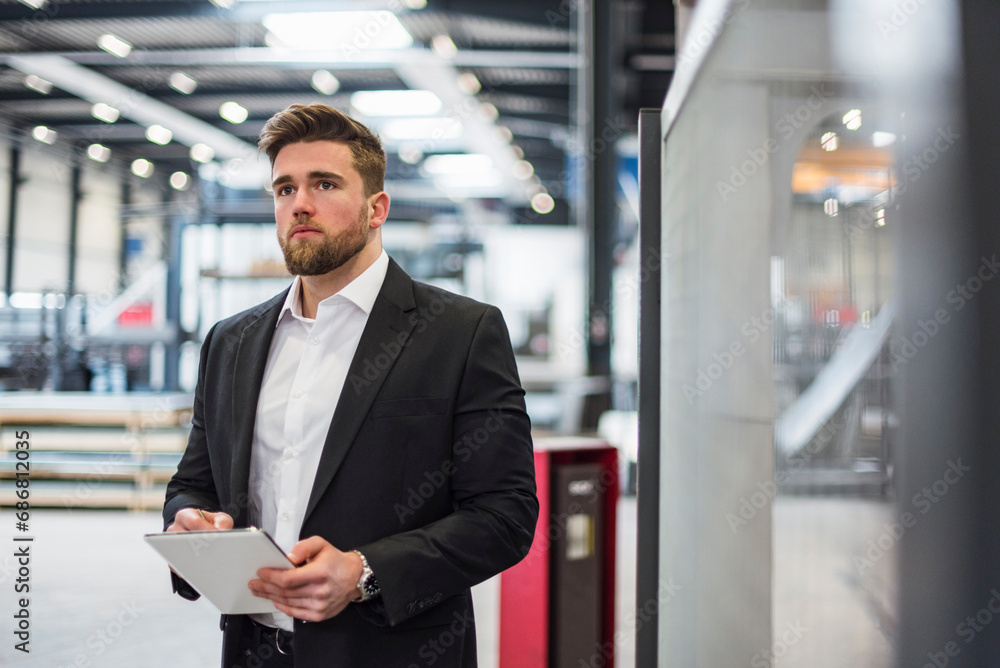 Businessman using tablet on factory shop floor Businessman using tablet on factory shop floor