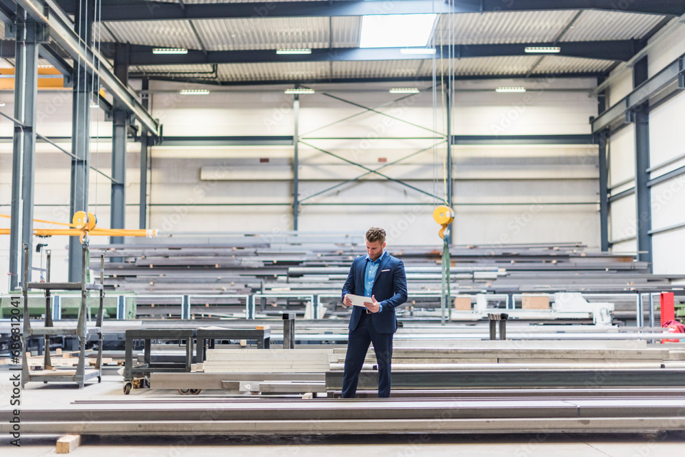 Businessman with tablet standing on factory shop floor Businessman with tablet standing on factory shop floor