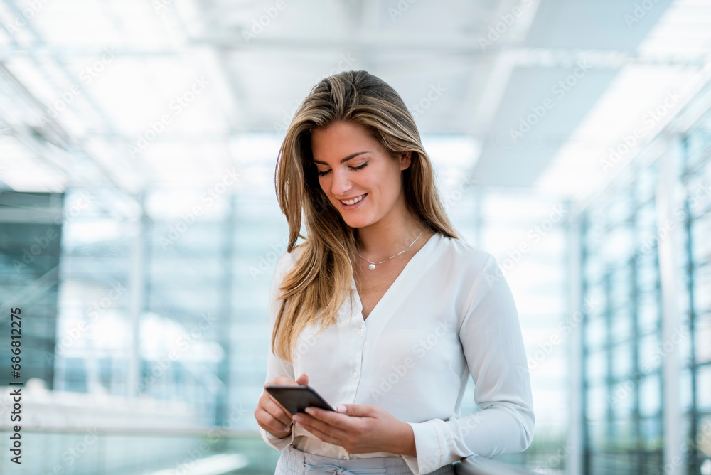 Smiling young woman standing at railing using cell phone Smiling young woman standing at railing using cell phone