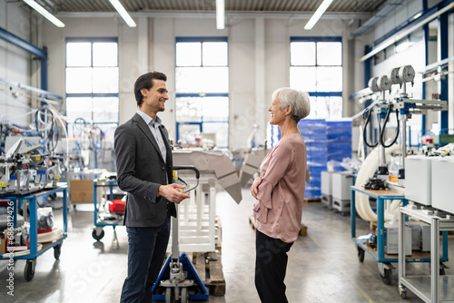 Smiling businessman and senior businesswoman talking in a factory photo
